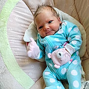 Cassie is registered to the contest to win money with this photo: baby, infant, blue_onesie, polka_dots, mitten, pink_mitten, cushion, seat, cozy, cute, smiling, face, head, newborn, child, soft_fabric, indoor, portrait, comfort, sleepy