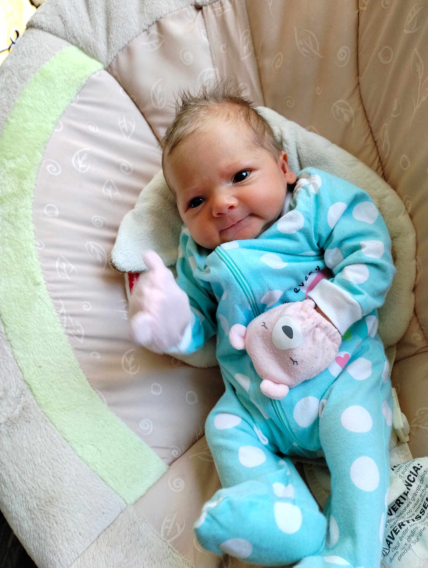 Cassie is registered to the contest to win money with this photo: baby, infant, blue_onesie, polka_dots, mitten, pink_mitten, cushion, seat, cozy, cute, smiling, face, head, newborn, child, soft_fabric, indoor, portrait, comfort, sleepy