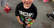 Nathaniel is registered to the contest to win money with this photo: child, boy, smile, minecraft, tshirt, indoor, carpet, casual_clothing, shoes, children, people, happy, standing, wristband, shorts, socks, floor, wooden_panel, legs, playful