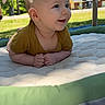 Aslan is registered to the contest to win money with this photo: baby, infant, play_mat, outdoor, greenery, plush_toy, elephant_toy, sunlight, smiling, curious, tummy_time, child, nature, daylight, grass, residential_area, clothing, happy, cute, portrait