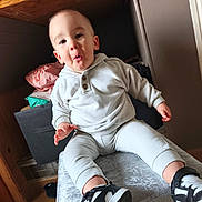 Soën participe au concours pour gagner de l'argent avec cette photo : baby, toddler, child, hoodie, sneakers, sitting, indoor, shelf, storage_box, stool, expression, cute, portrait, hand, legs, clothing, wood_floor, casual_shoes, curiosity, smile