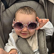 Esmée a rejoint le concours — aidez-le/la à gagner de superbes lots ! accessory, adult, baby, child, clothing, comfort, cute, fabric, hand, happy, holding, infant, person, playful, portrait, seatbelt, smile, stroller, sunglasses, transport