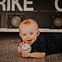baby, baseball, child, floor, black_clothing, tongue_out, happy, indoor, sports, playful, portrait, crawling, young_child, smiling, person, head, face, short_hair, light_skin, toy