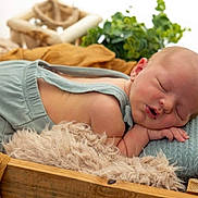 Maxime a rejoint le concours — aidez-le/la à gagner de superbes lots ! newborn, baby, sleeping, infant, blue_overalls, wooden_crate, blanket, pillow, cozy, soft_texture, knitted, fur, resting, peaceful, indoors, natural_light, closeup, portrait, child, cute