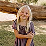 child, girl, blonde_hair, smile, outdoor, grass, tree, log, sunlight, dress, portrait, nature, happy, person, young, casual, standing, daylight, cute, innocent