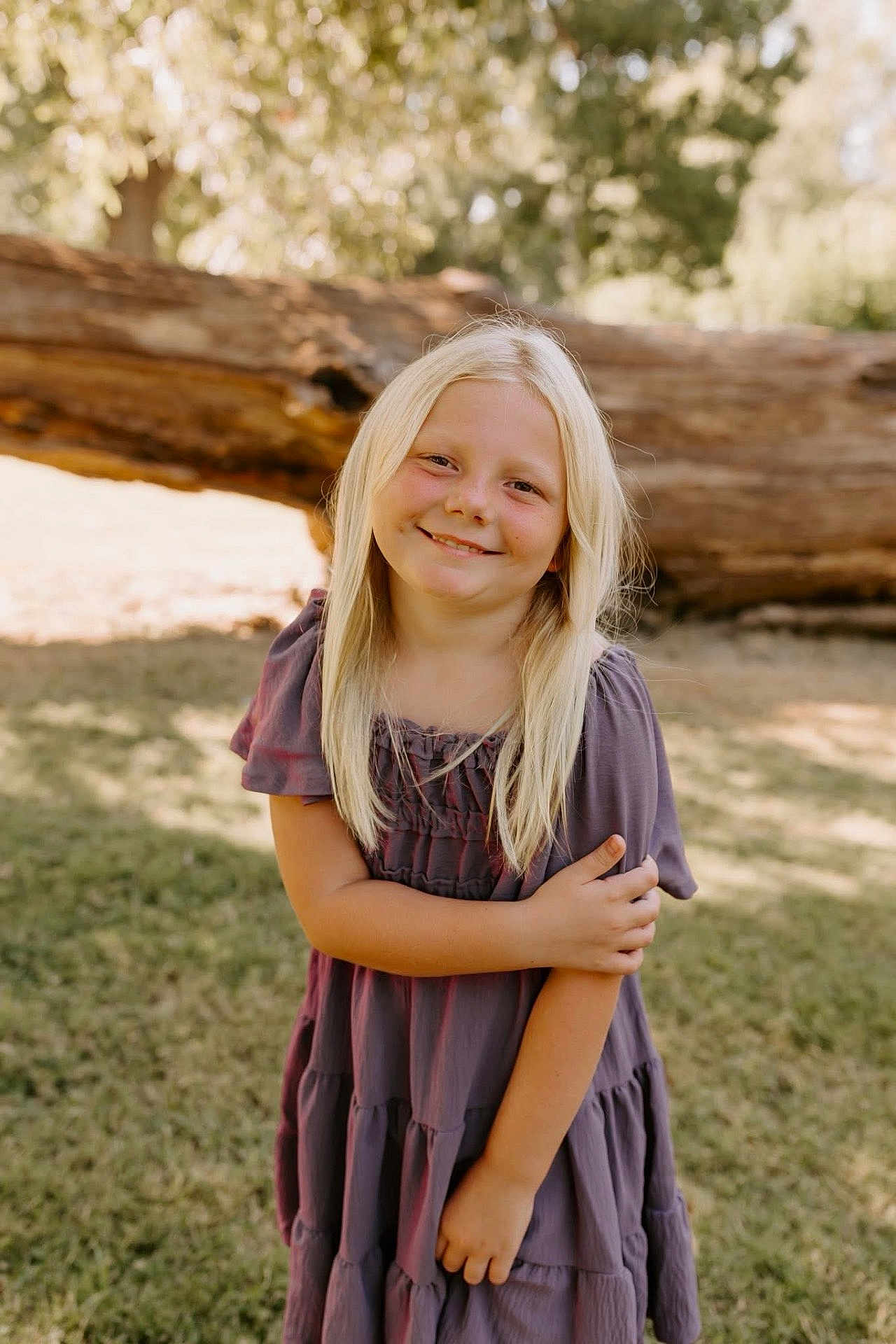 Rylie joined the competition — help win amazing prizes! child, girl, blonde_hair, smile, outdoor, grass, tree, log, sunlight, dress, portrait, nature, happy, person, young, casual, standing, daylight, cute, innocent