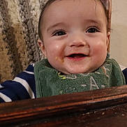 Liam is registered to the contest to win money with this photo: baby, infant, child, smile, bib, food, messy, cheeks, eyes, closeup, portrait, highchair, wooden_tray, blanket, striped_sleeve, indoor, adorable, drool, eyelashes, happy