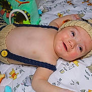 Liam is registered to the contest to win money with this photo: baby, child, knitted_hat, striped_clothing, blanket, toy, smile, lying_down, cute, infant, face, happy, soft_toy, colorful, indoor, playtime, young_child, headwear, portrait, cozy