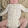 baby, infant, onesie, blanket, diaper, face, person, skin, hand, foot, tattoo, pattern, clothing, laying, indoor, cute, cozy, expression, newborn, soft