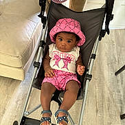 Jream joined the competition — help win amazing prizes! baby, baby_fan, black_hair, child, couch, curious_expression, flooring, footwear, furniture, indoor, legs, looking_at_camera, person, pink_hat, pink_shorts, sandals, seated, stroller, white_top, wood_floor