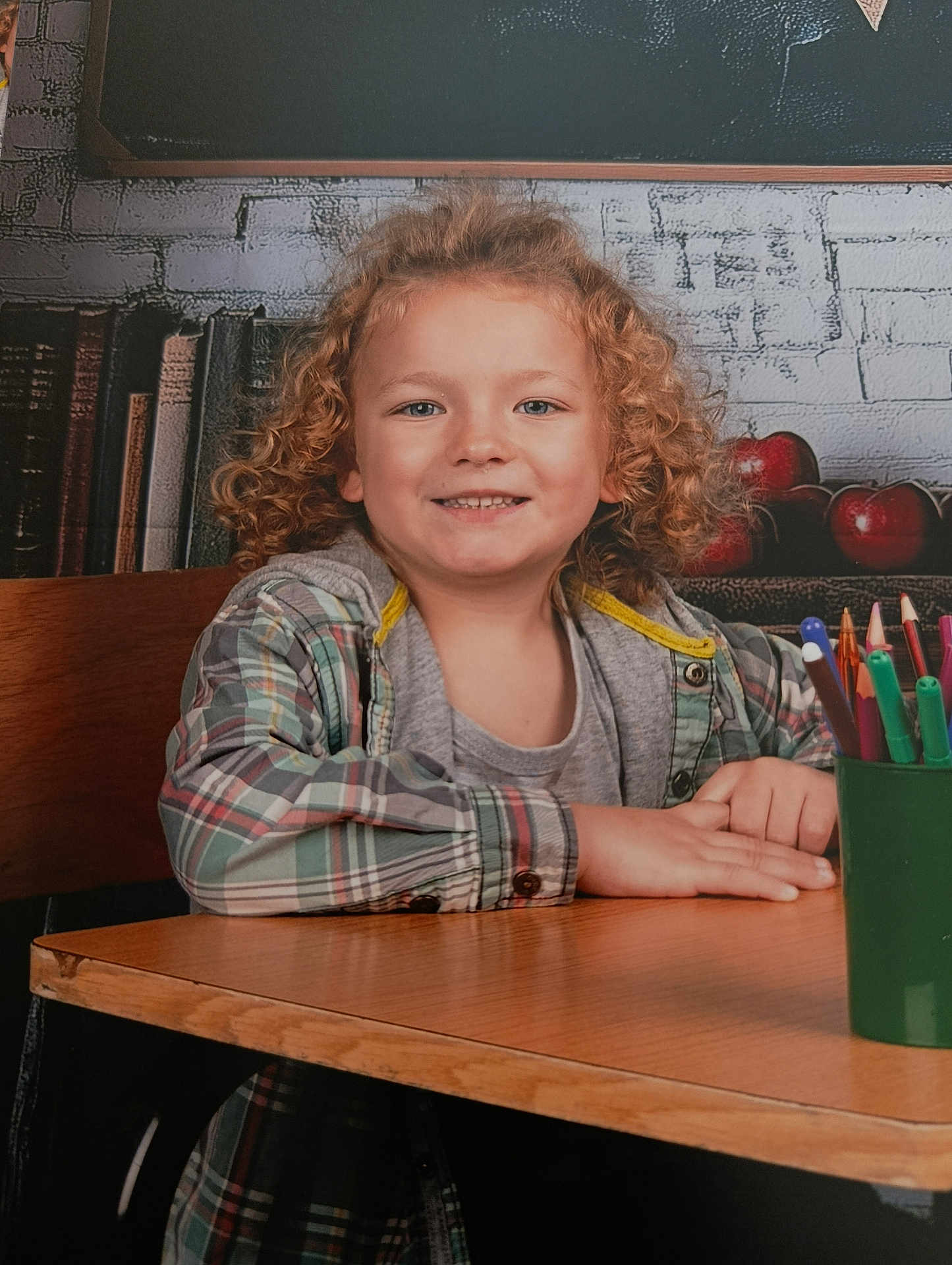 Abel a rejoint le concours — aidez-le/la à gagner de superbes lots ! apples, background_wall, books, chalkboard, child, classroom, colored_pencils, crayons, curly_hair, desk, hands, jacket, pencil_holder, plaid_shirt, portrait, school_portrait, seat, smile, student, wooden_table