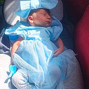 Meadow is registered to the contest to win money with this photo: baby, sleeping, blue_dress, headband, bow, cushion, soft_light, infant, cozy, newborn, cute, child, indoors, portrait, clothing, peaceful, resting, fabric, sock, seat