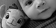 Namron participe au concours pour gagner de l'argent avec cette photo : baby, child, plush_toy, stuffed_animal, knitted_sweater, black_and_white, closeup, face, eyes, cozy, cute, portrait, indoors, soft_toy, smile, infant, person, expression, texture, warm