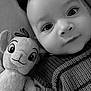 baby, child, plush_toy, stuffed_animal, knitted_sweater, black_and_white, closeup, face, eyes, cozy, cute, portrait, indoors, soft_toy, smile, infant, person, expression, texture, warm