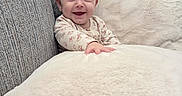 Kali is registered to the contest to win money with this photo: baby, smiling, couch, blanket, pillow, infant, cozy, happy, indoor, child, face, hand, soft, texture, furniture, portrait, cute, young, comfort, relaxing