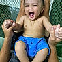 baby, child, smiling, laughing, blue_shorts, gold_necklace, cross, hands, adult, mesh_background, happy, bare_chest, person, skin, legs, indoors, holding, joyful, playful, portrait