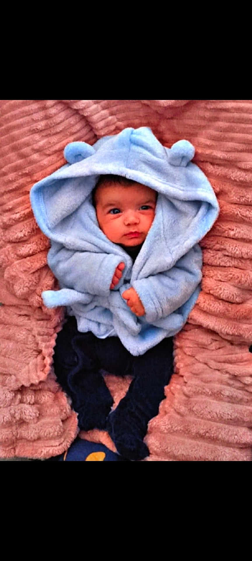 Leāo participe au concours pour gagner de l'argent avec cette photo : baby, infant, blue_hooded_jacket, bear_ears, blanket, pink_blanket, cute, child, newborn, soft_texture, warm_clothing, lying_down, portrait, small_hands, indoors, cozy, adorable, face, looking, young_child