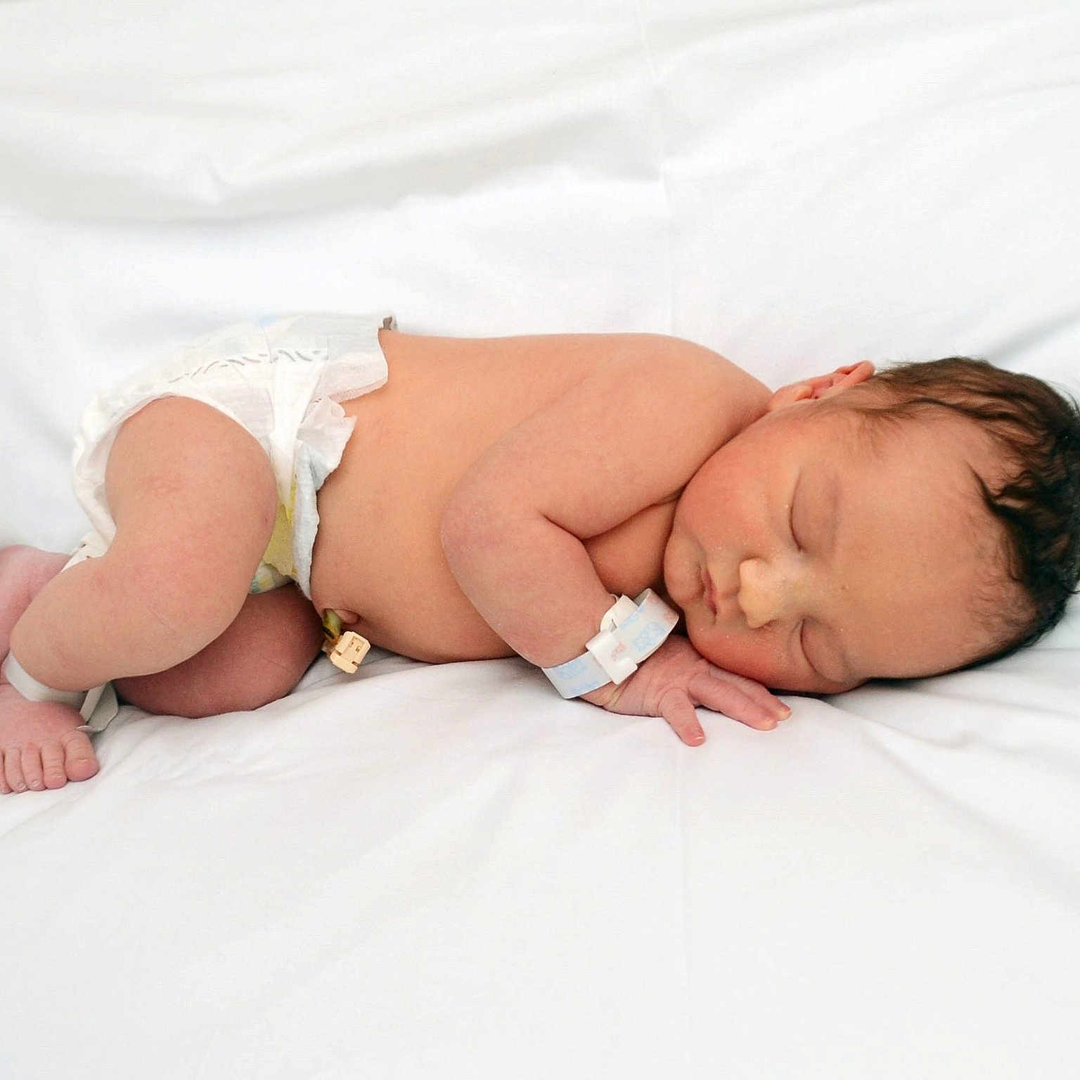 Reid is registered to the contest to win money with this photo: newborn, baby, sleeping, diaper, infant, hospital_bracelet, skin, peaceful, white_blanket, lying_down, cute, small, resting, child, human, healthcare, fresh, soft, tender, closeup