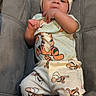 baby, infant, toddler, tigger, pajamas, hat, onesie, footed_pajamas, couch, gray_couch, indoor, cute, child, person, clothing, face, hand, relaxed, seated, looking
