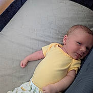 Nikolai is registered to the contest to win money with this photo: baby, infant, yellow_onesie, dinosaur_pants, playpen, soft_surface, sleepwear, child, newborn, cute, resting, indoor, portrait, small_hands, relaxed, face, skin, head, lying_down, clothing