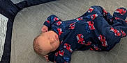 Nikolai joined the competition — help win amazing prizes! newborn, baby, sleeping, onesie, fire_truck, blue_clothing, red_pattern, quilted_surface, gray_background, infant, peaceful, relaxed_pose, indoor, closeup, face, head, hands, soft_lighting, child, portrait