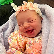 Heavenley joined the competition — help win amazing prizes! newborn, baby, smiling, flower_headband, blanket, floral_outfit, cozy, indoor, soft_texture, wrapped, infant, cute, happy, child, portrait, head, face, sleepy, peaceful, clothing