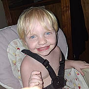 Hannah is registered to the contest to win money with this photo: child, toddler, smile, high_chair, harness, blonde_hair, blue_eyes, face, messy, food, indoor, person, baby, cute, happy, furniture, seat, seatbelt, closeup, skin