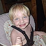 child, toddler, smile, high_chair, harness, blonde_hair, blue_eyes, face, messy, food, indoor, person, baby, cute, happy, furniture, seat, seatbelt, closeup, skin