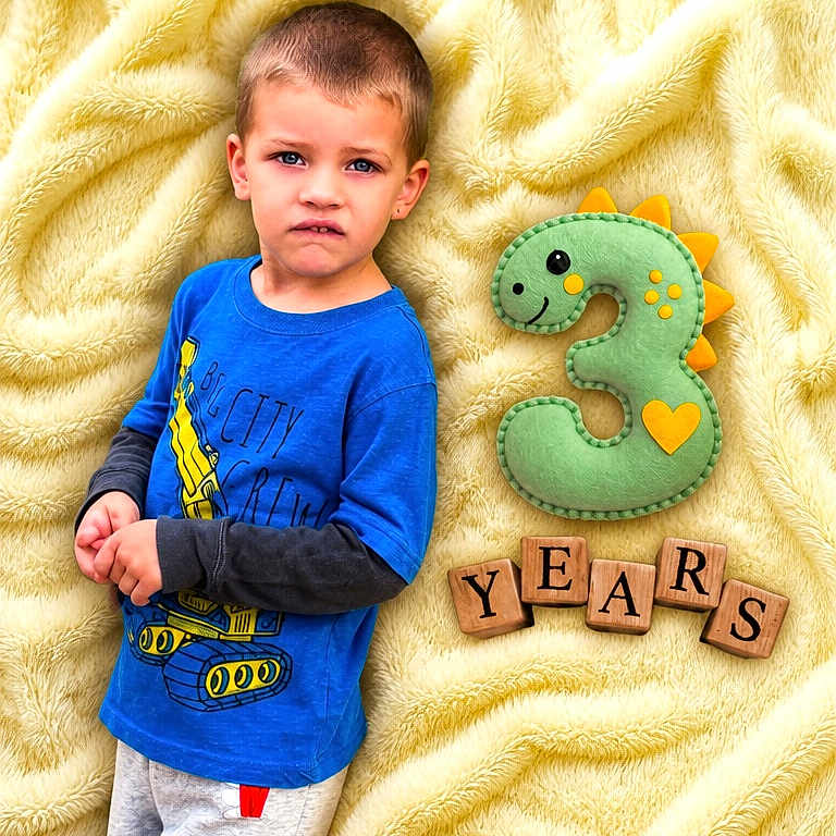 Jj is registered to the contest to win money with this photo: child, boy, blue_shirt, gray_pants, yellow_blanket, plush_toy, number_three, wooden_blocks, birthday, celebration, indoor, portrait, curious_expression, casual_clothing, soft_texture, smiling_toy, age_three, cute, young_child, person