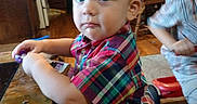 Jj joined the competition — help win amazing prizes! toddler, child, plaid_shirt, indoor, kitchen, table, wooden_table, carpet, playing_child, furniture, blue_eyes, curly_hair, person, young_child, home, casual_clothing, expression, standing, toy, background