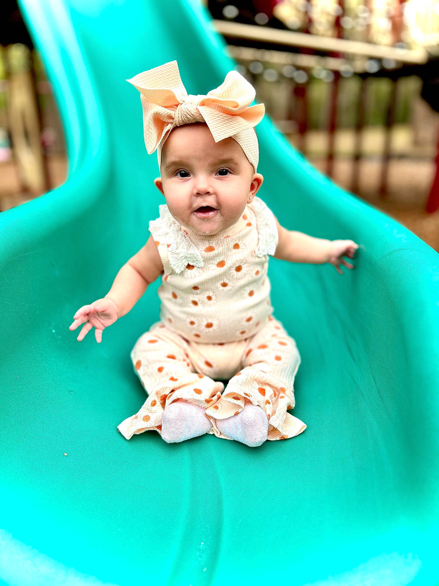 Riverlyn is registered to the contest to win money with this photo: baby, bonnet, cap, clothing, dress, face, hat, head, indoors, outdoorplayarea, outdoors, pants, person, photography, playarea, portrait, sitting, slide, sliding, toy