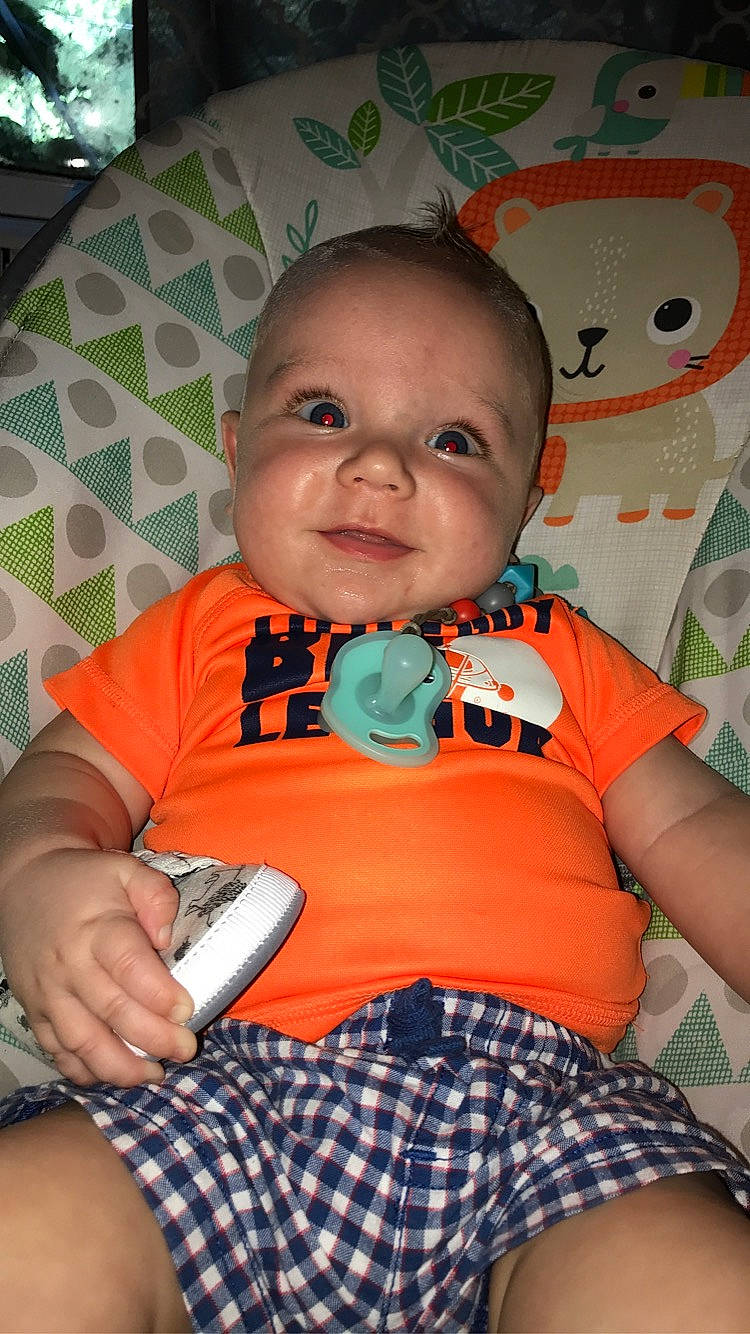 Braxton is registered to the contest to win money with this photo: arm, baby, baby_toddler_clothing, cheek, chin, face, facial_expression, finger, happy, head, iris, mouth, neck, nose, orange, organ, person, skin, sleeve, smile