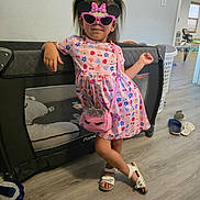 Layla Montoya joined the competition — help win amazing prizes! child, girl, sunglasses, dress, pink_purse, unicorn, playpen, room, floor, slippers, photoframe, wall, hair_ties, sandals, standing, posing, indoor, casual, confident, colorful