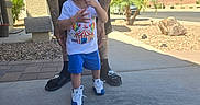 Gabriel is registered to the contest to win money with this photo: toddler, child, birthday_crown, toy, adult, tattoos, white_tshirt, blue_shorts, sneakers, outdoor, sunny, driveway, suburban, palm_trees, sidewalk, photography, person, hand, phone, casual