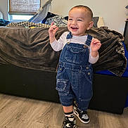 Gabriel joined the competition — help win amazing prizes! toddler, child, denim_overalls, sneakers, laughing, standing, indoor, bed, blanket, window, flooring, happy, person, cute, smiling, earrings, casual_clothing, home, natural_light, young
