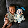 Amari joined the competition — help win amazing prizes! baby, child, couch, leather, plush_toy, mickey_mouse, toy, smile, sitting, clothing, infant, indoor, cute, person, portrait, happy, furniture, block, number, months