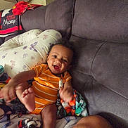 Amari joined the competition — help win amazing prizes! baby, blanket, child, colorful, couch, cozy, cute, furniture, happy, home, indoor, infant, mickey_mouse, orange_onesie, person, pillow, playful, relaxing, smiling, soft