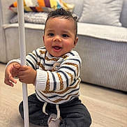 Isaiah participe au concours pour gagner de l'argent avec cette photo : bear_pattern, child, colorful_pillow, couch, cozy, curly_hair, cushions, cute, dark_pants, happy, home, indoor, portrait, sitting, smiling, socks, striped_sweater, toddler, white_pole, wooden_floor