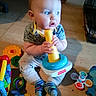 James joined the competition — help win amazing prizes! baby, child, toy, colorful, floor, indoor, sitting, curious, stacking_toy, clothing, socks, playtime, hand, face, expression, wooden_floor, infant, cute, bright, young