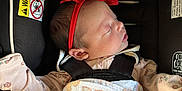 Bayler joined the competition — help win amazing prizes! newborn, baby, sleeping, car_seat, red_bow, blanket, butterfly_pattern, infant, clothing, headband, safety_harness, close_up, indoors, peaceful, resting, child, face, person, cute, soft_lighting