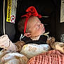 newborn, baby, sleeping, car_seat, red_bow, blanket, butterfly_pattern, infant, clothing, headband, safety_harness, close_up, indoors, peaceful, resting, child, face, person, cute, soft_lighting