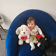 Ayline a rejoint le concours — aidez-le/la à gagner de superbes lots ! baby, child, stuffed_toy, plush, blue_chair, indoor, smiling, cute, person, toy_dog, mickey_mouse, floor, white_wall, clothing, sitting, happy, soft_toy, homedecor, bag, cozy