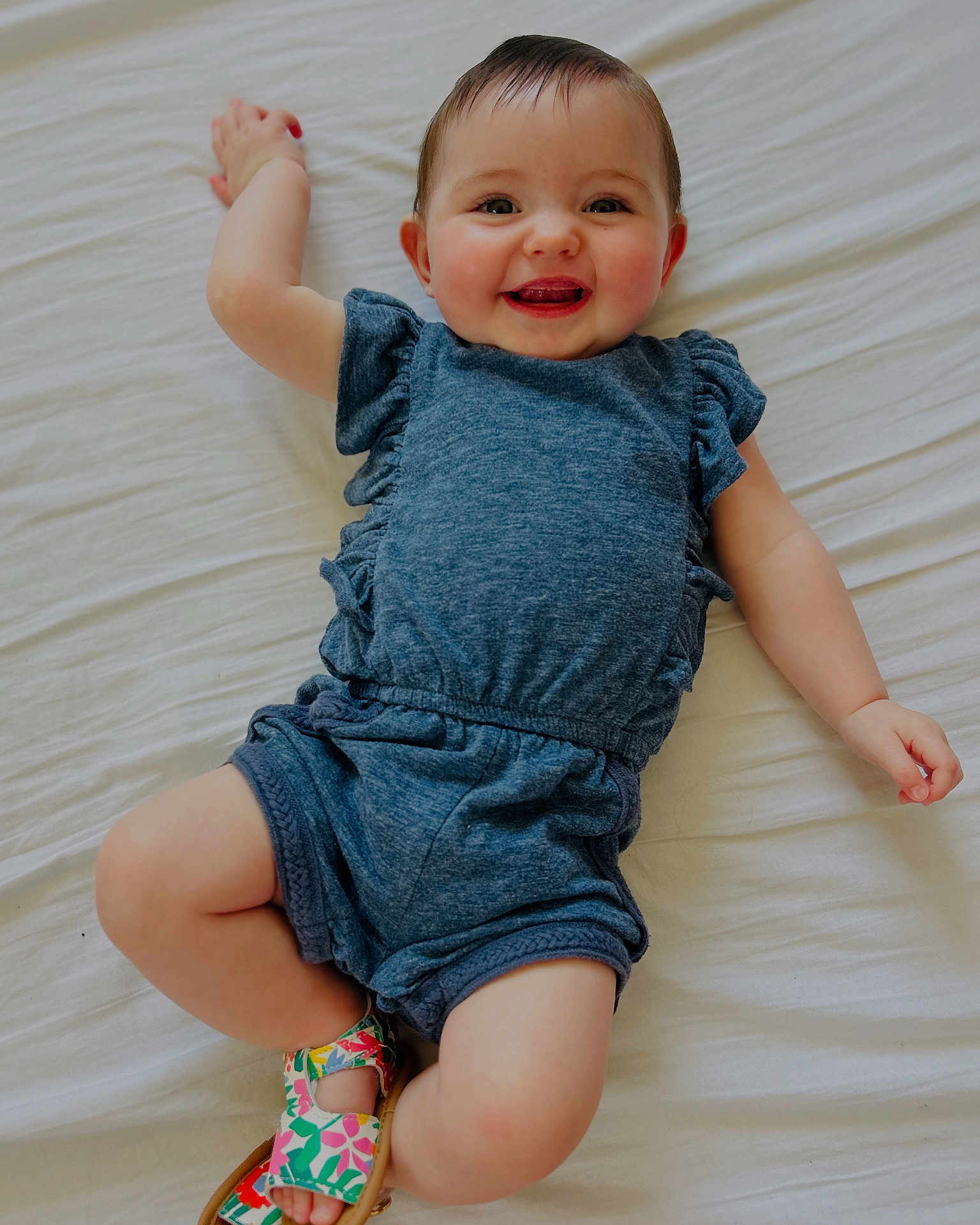Thea a rejoint le concours — aidez-le/la à gagner de superbes lots ! baby, smiling, infant, blue_clothing, sandals, lying_down, white_sheet, cute, happy, child, portrait, skin, footwear, one_person, indoors, young_child, casual_clothing, baby_girl, playful, relaxed