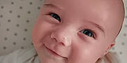 Jameson is registered to the contest to win money with this photo: baby, smiling, face, infant, cute, eyes, white_clothing, blanket, star_pattern, closeup, portrait, child, adorable, happy, skin, head, young, lying_down, soft, babywear
