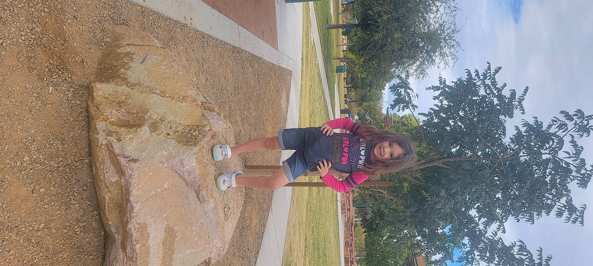 Abby is registered to the contest to win money with this photo: adventure, concrete, facade, fun, hat, joy, landscape, leisure, line, person, plant, recreation, shadow, sky, smile, t_shirt, tree, vacation, walking_shoe, wood