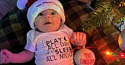 Giovanni joined the competition — help win amazing prizes! baby, santa_hat, christmas_ornament, plush_toy, blanket, christmas_tree, holiday, festive, lights, floor, clothing, infant, smile, cute, indoors, celebration, decoration, person, happy, seasonal
