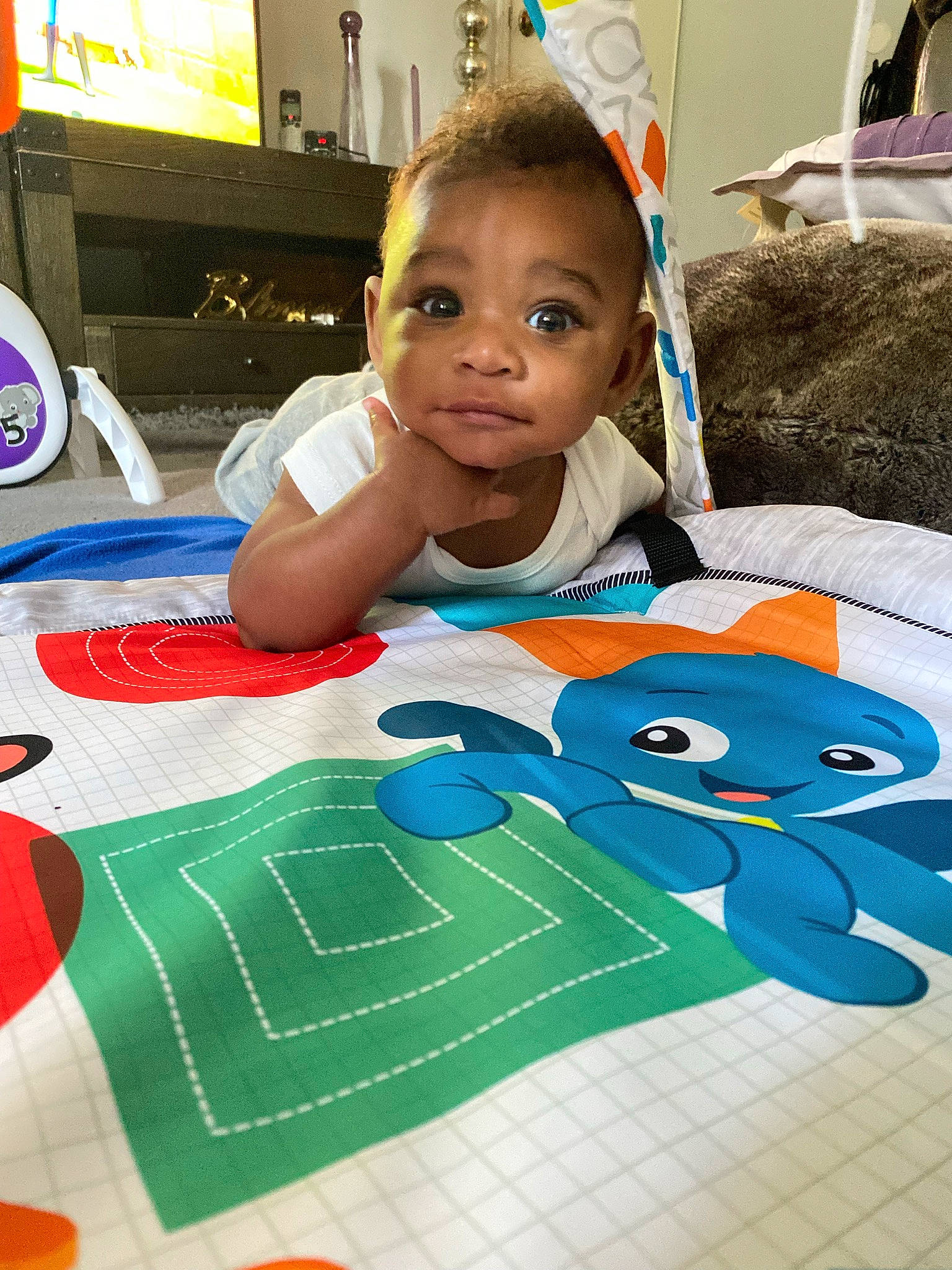 Omari is registered to the contest to win money with this photo: audio_equipment, baby, chair, child, desk, display_device, event, flooring, fun, home_appliance, indoor_games_and_sports, learning, leisure, linens, pattern, person, play, recreation, room, t_shirt