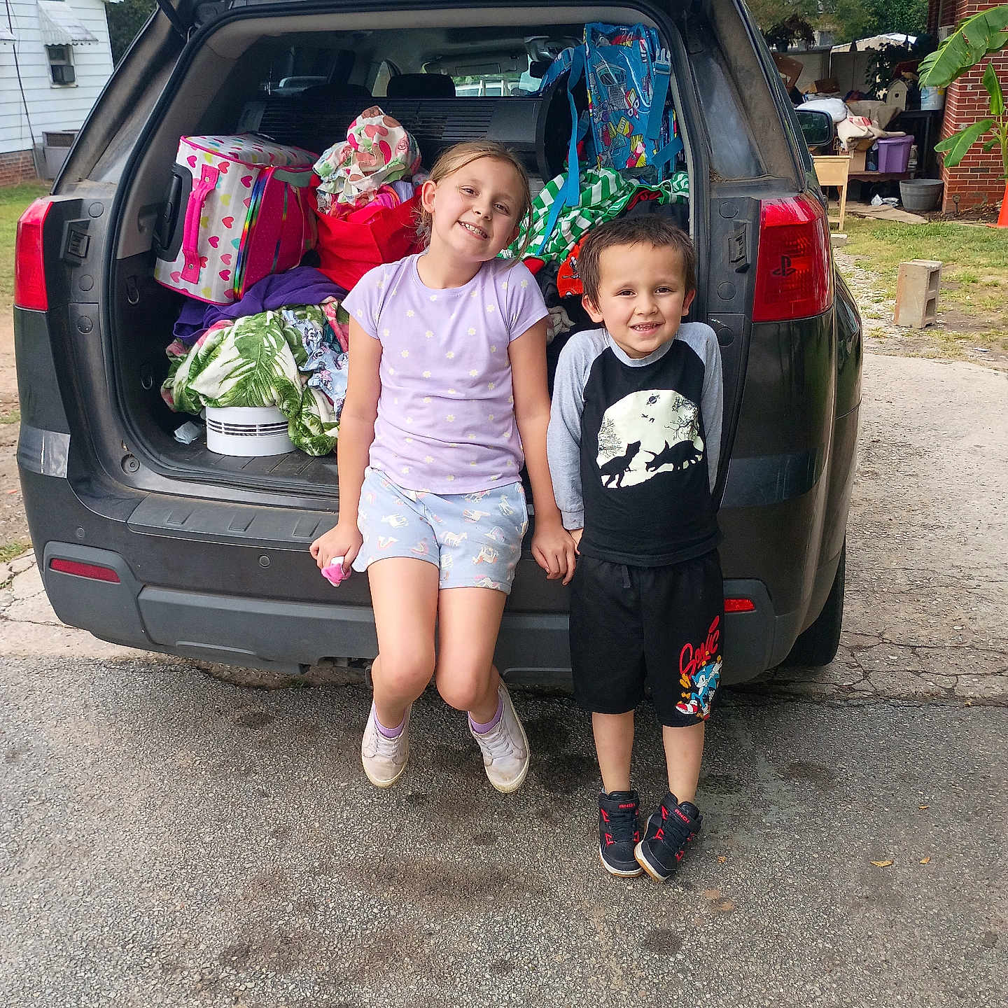 Brent'Lee joined the competition — help win amazing prizes! backpack, bags, car_trunk, casual_clothes, children, concrete, daytime, family, footwear, greenery, happy, holding_hands, kids, outdoor, playful, residential_area, sibling, smiling, summer_clothes, transportation