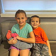 Serenity is registered to the contest to win money with this photo: child, children, baby, newborn, sibling, couch, indoor, smile, happy, holding, striped_blanket, orange_shirt, camouflage_pants, headband, shorts, portrait, family, together, seated, casual_clothing