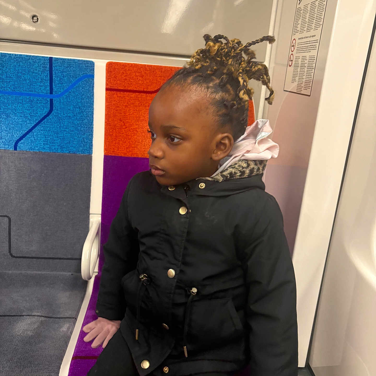 Emel a rejoint le concours — aidez-le/la à gagner de superbes lots ! black_clothing, braided_hair, casual, child, coat, colorful_seat, gloves, hair_style, indoor, person, portrait, public_space, public_transport, seat, seated, subway, thoughtful, transportation, urban, young_child
